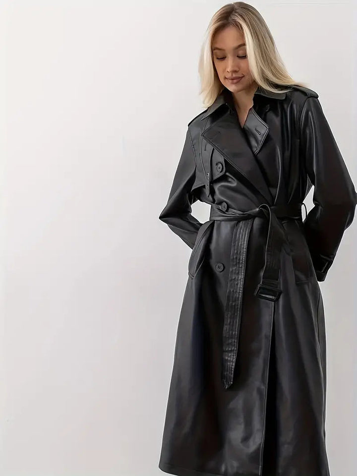 Women’s long black faux-leather trench coat with double-breasted design and tie waist.