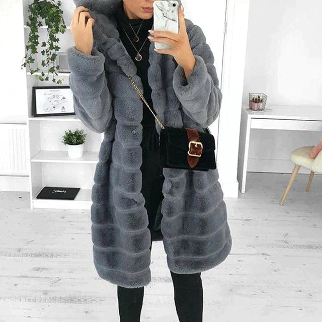 Women’s long grey faux-fur hooded coat styled with a black crossbody bag