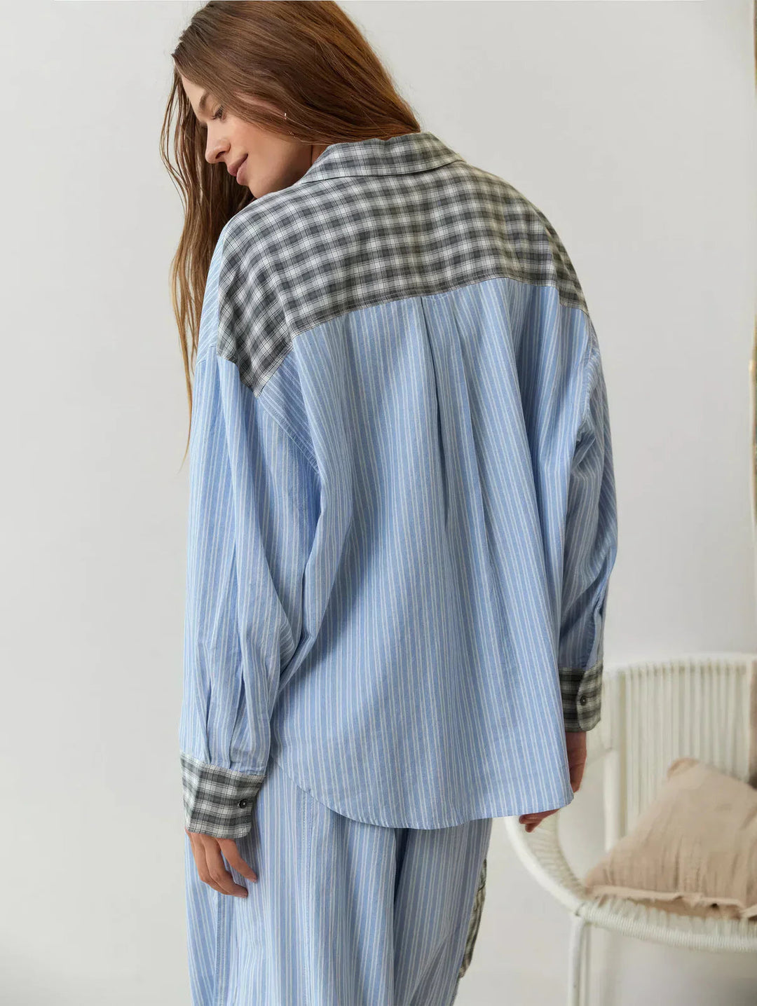 Woman wearing a blue and plaid pajama set in a minimalistic room.